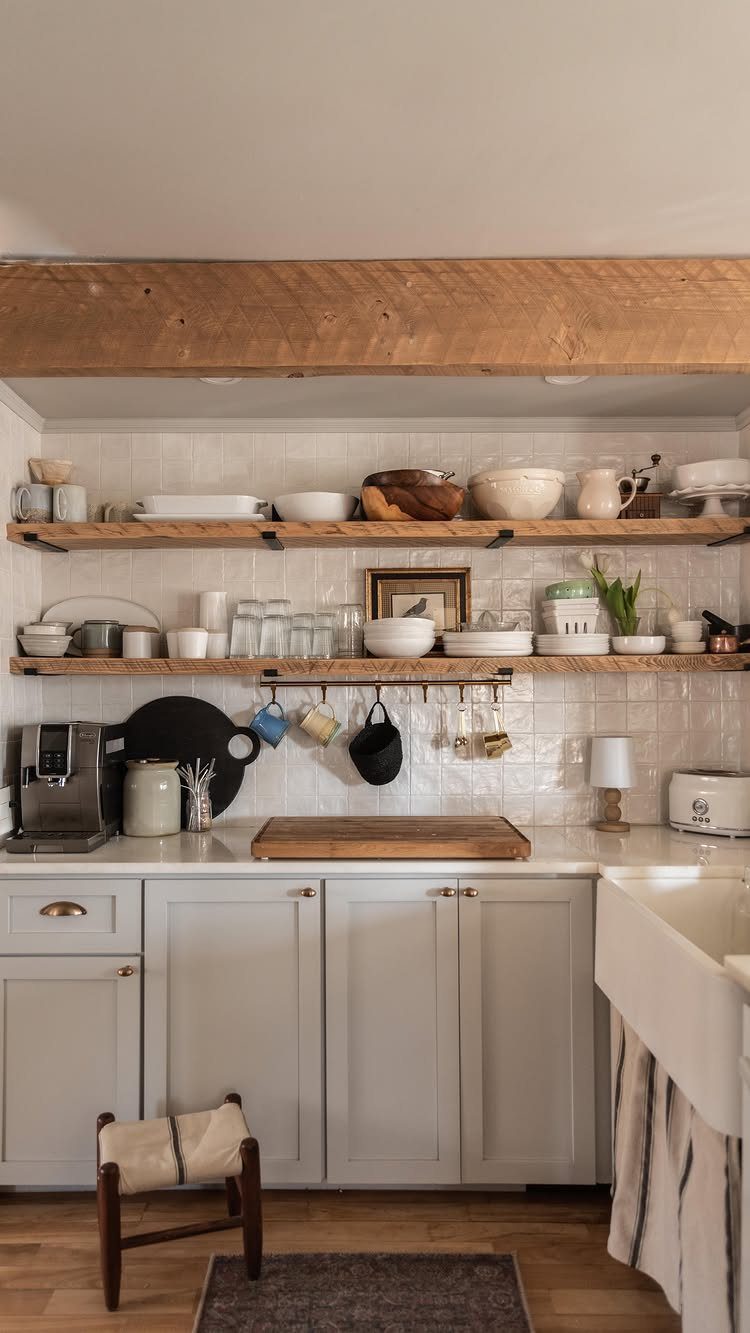Wooden open shelves with white dishes above light grey kitchen cabinets and countertop.