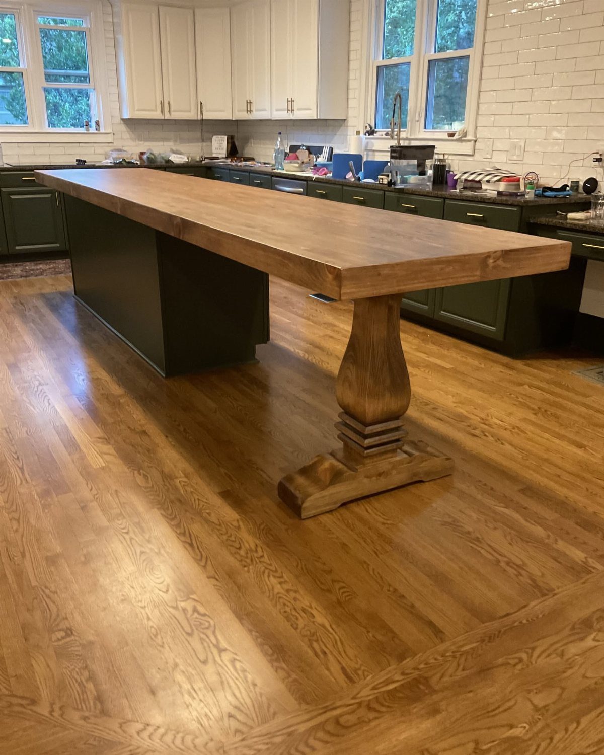 Kitchen island with a thick wooden top and a carved pedestal leg support.