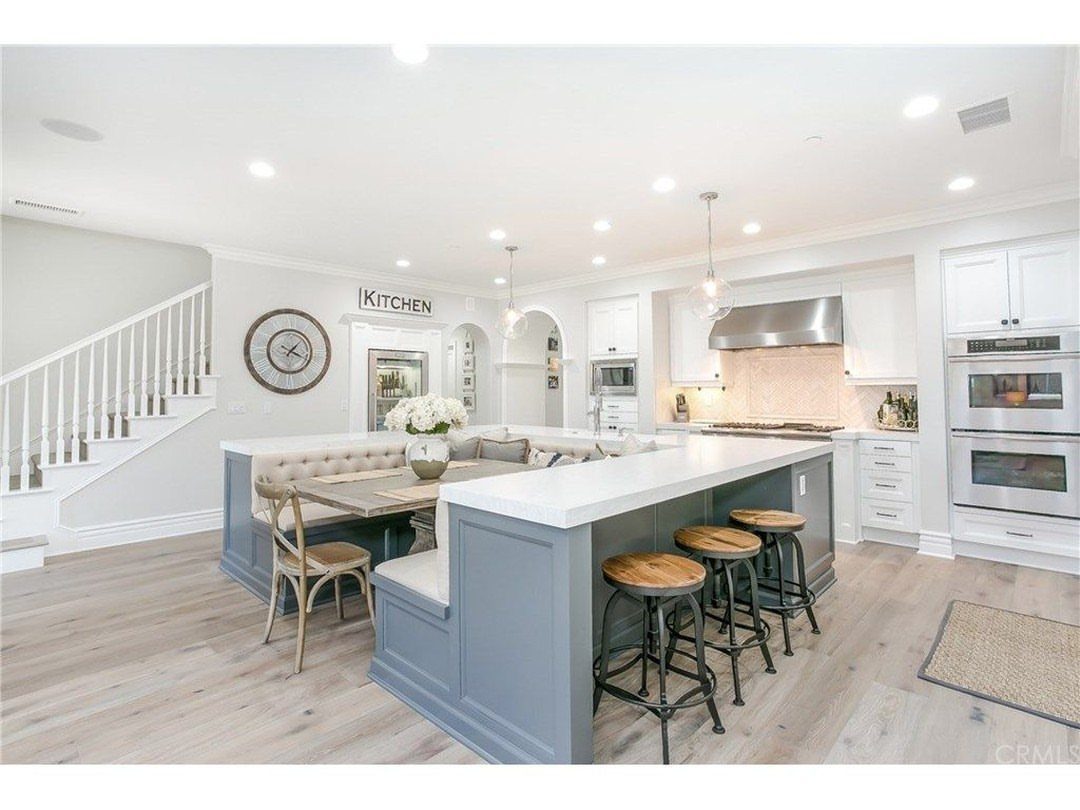 Blue kitchen island connected to a wooden dining table with L-shaped banquette seating.