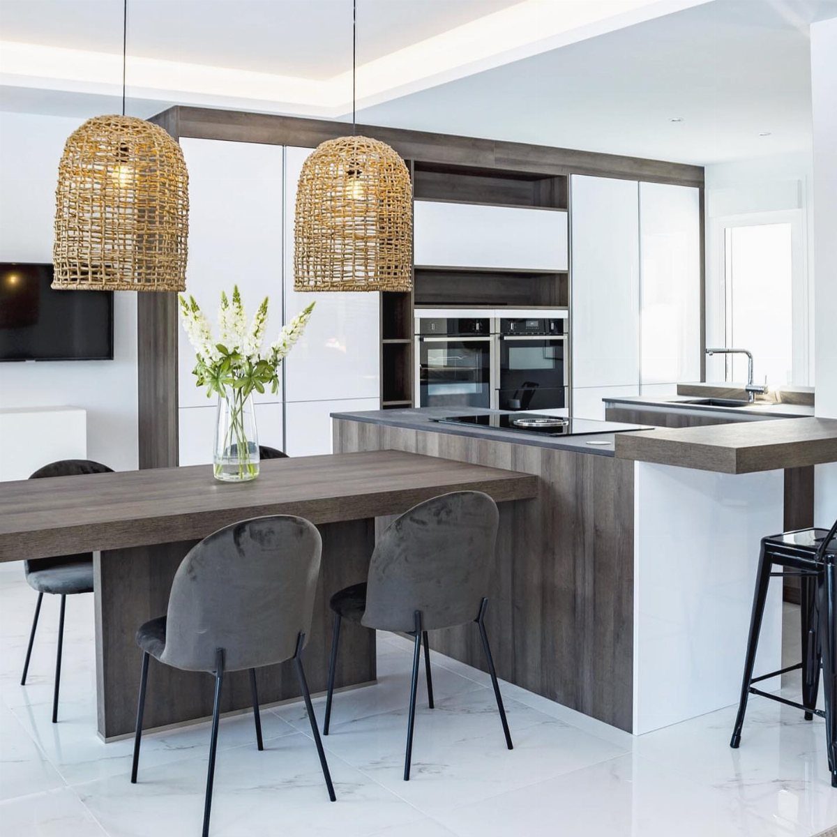 Dark wood dining table attached perpendicularly to a white modern kitchen island