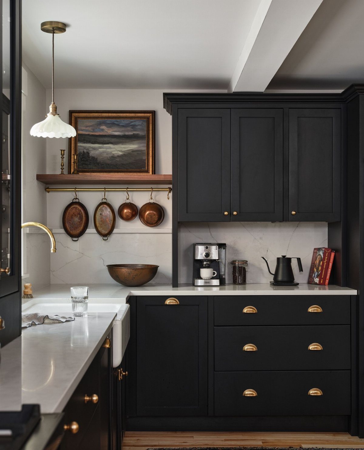 Black kitchen cabinets with gold handles and white marble countertops in a classic kitchen.