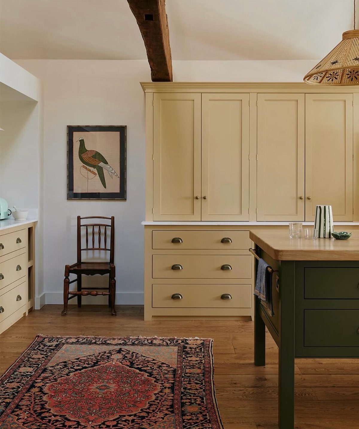 Pale yellow kitchen cabinets with a white countertop and a dark green island.
