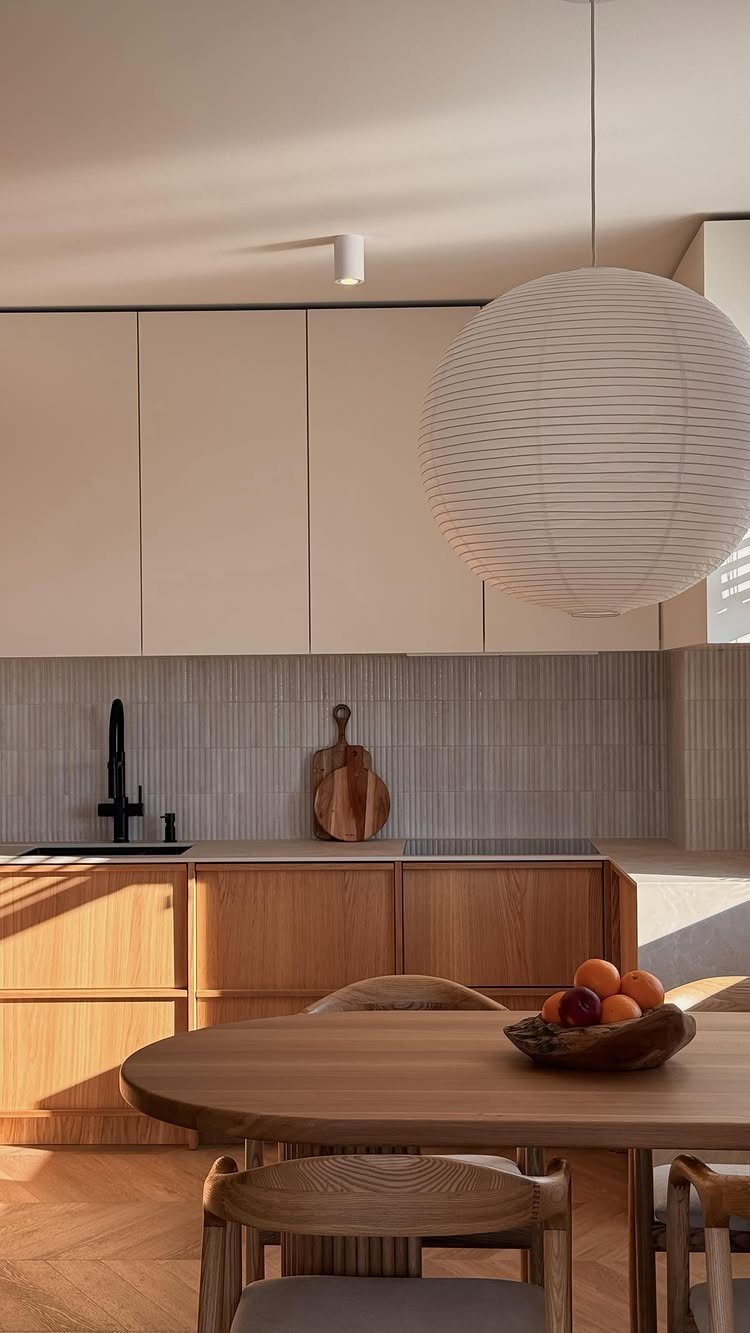 Natural wood lower kitchen cabinets with a matching wooden dining table and chairs.