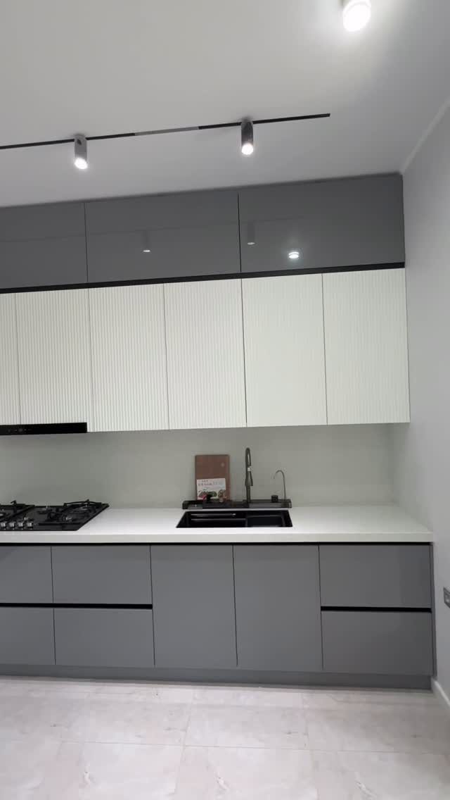 Modern kitchen with grey and white two-tone cabinets and white countertops.