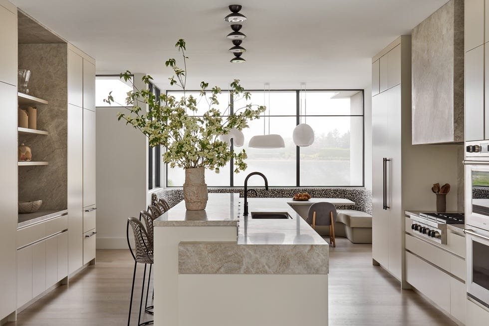 Two-tier white kitchen island with marble accents and a vase of greenery.