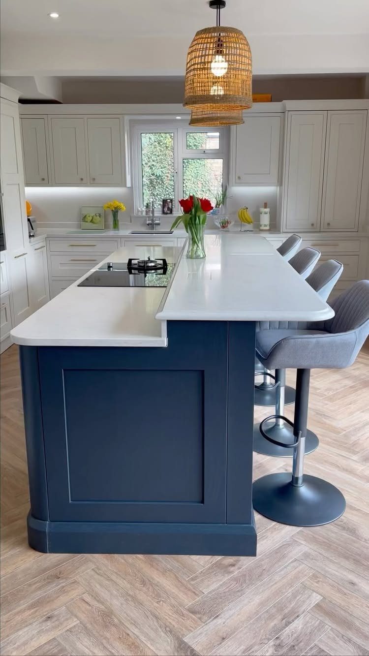 Navy blue split-level kitchen island with white countertops and grey bar stools.