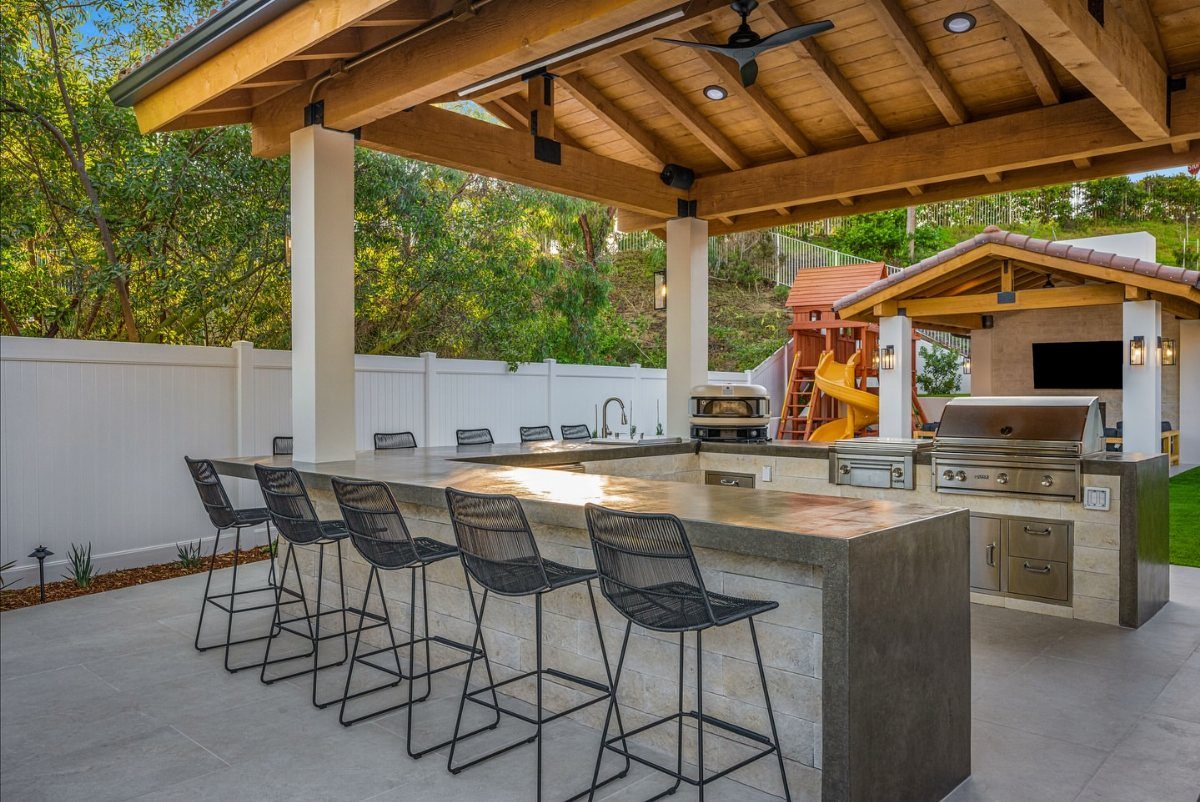 Outdoor kitchen island with two levels, raised bar seating, and built-in grill.
