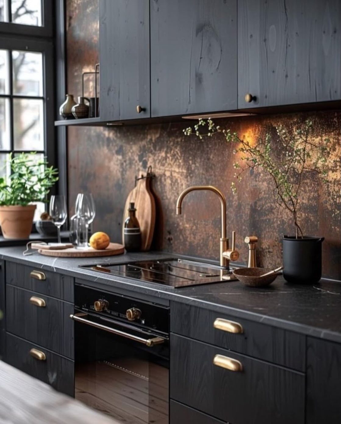 Black lower cabinets with gold hardware and dark gray upper cabinets in a kitchen.