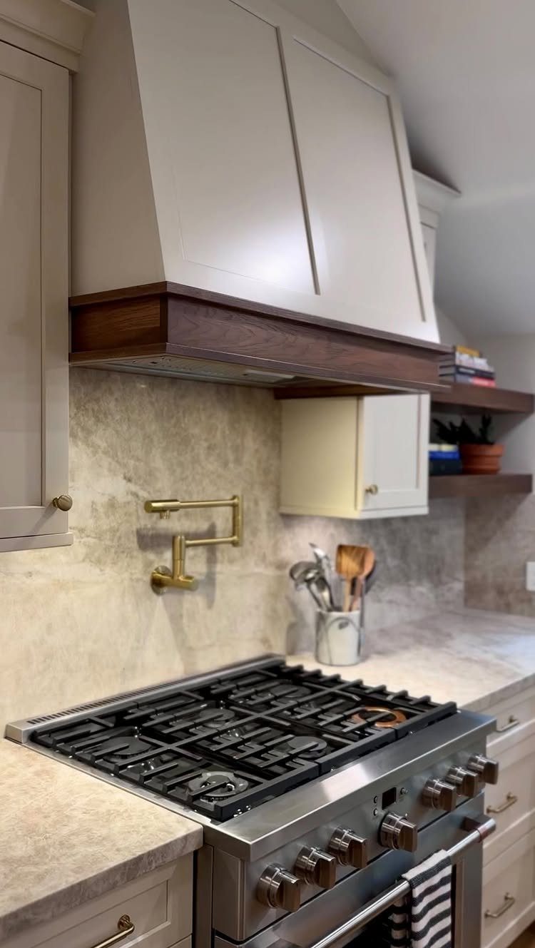 White kitchen cabinets and range hood with dark wood trim and stainless steel stove