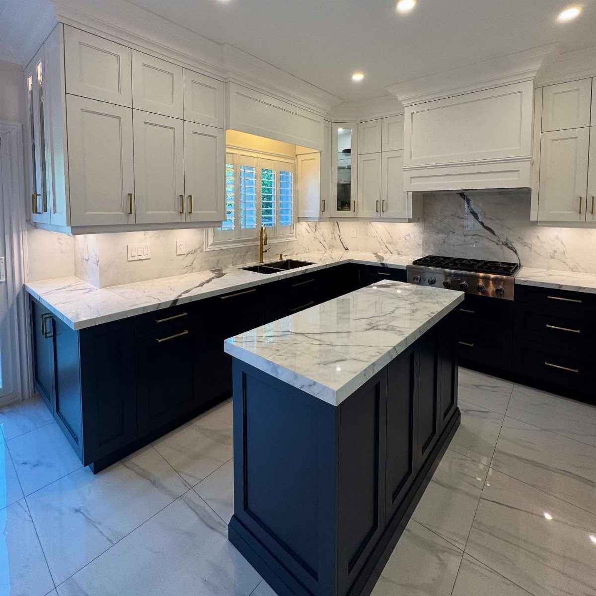 Navy blue lower cabinets and cream upper cabinets with white marble countertops.