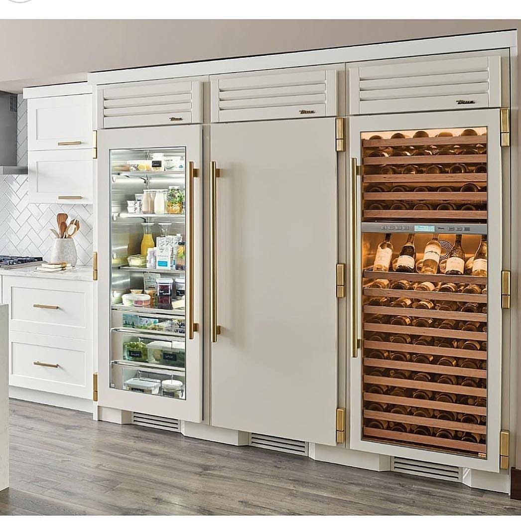 White built-in kitchen appliances with gold handles and a wine cooler.