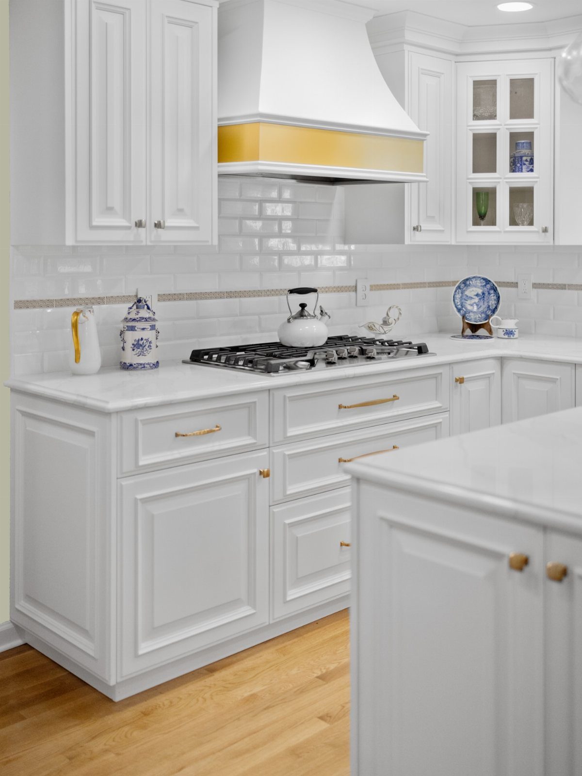 White kitchen cabinets with gold handles and a white gas stovetop.