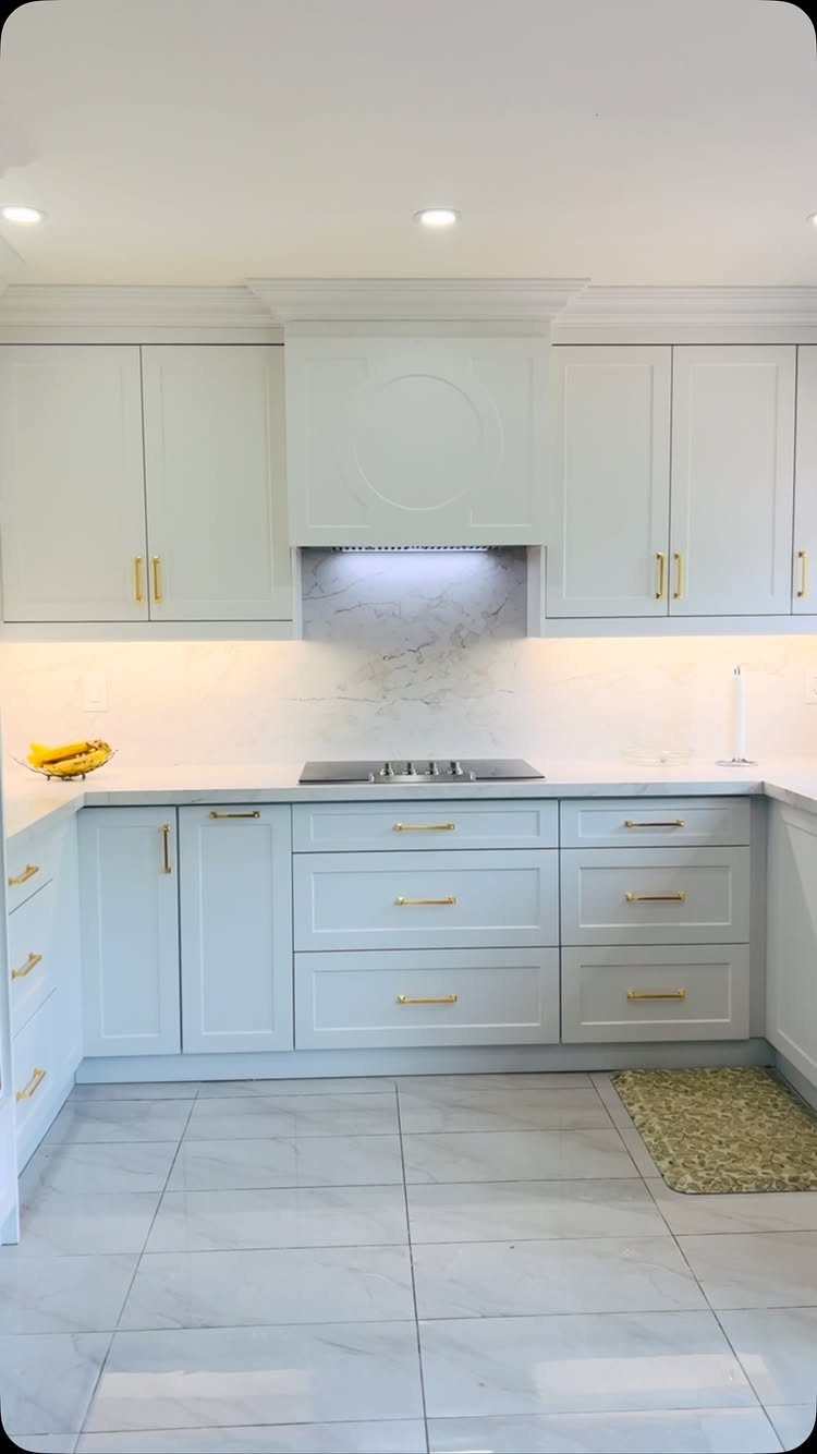 White shaker cabinets with gold handles in a bright, modern kitchen setting.