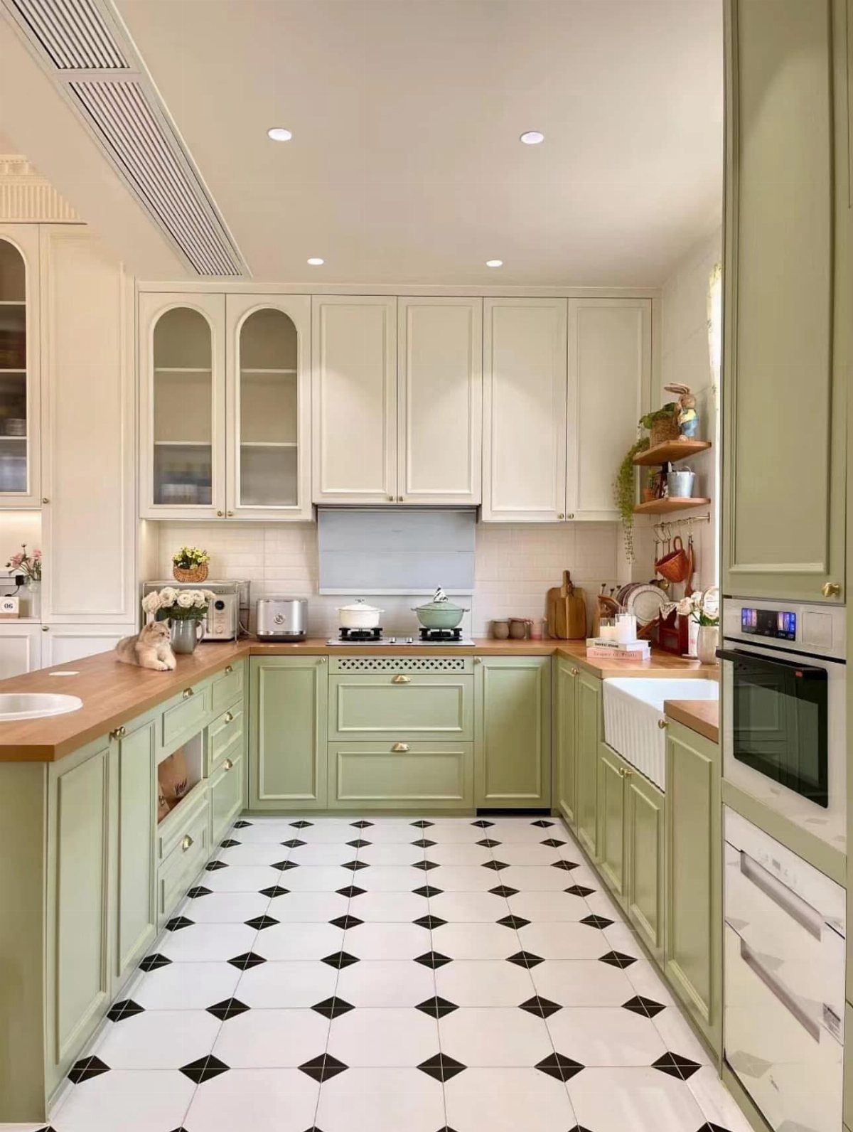 Butcher block countertops paired with sage green lower and white upper kitchen cabinets.