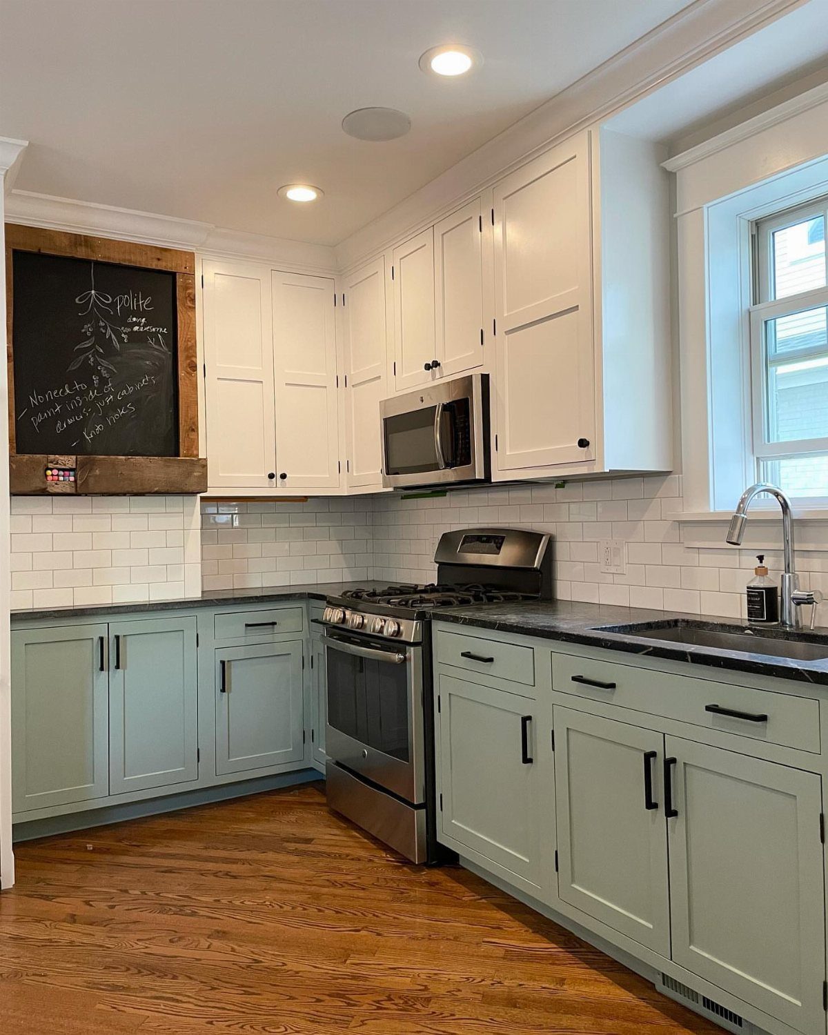 Sage green lower cabinets and white upper cabinets in a bright modern kitchen