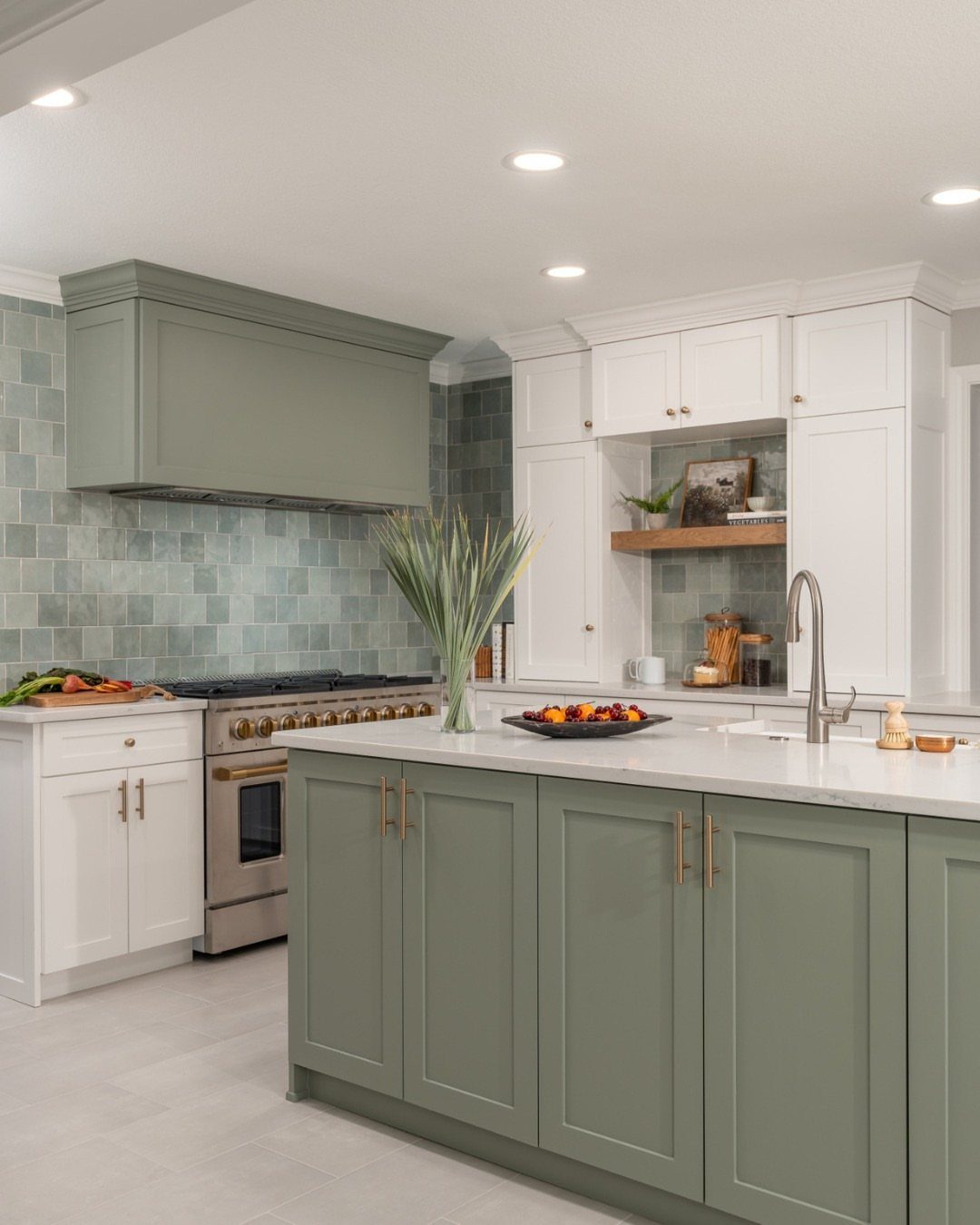 Sage green and white kitchen cabinets with a white countertop and tiled backsplash.