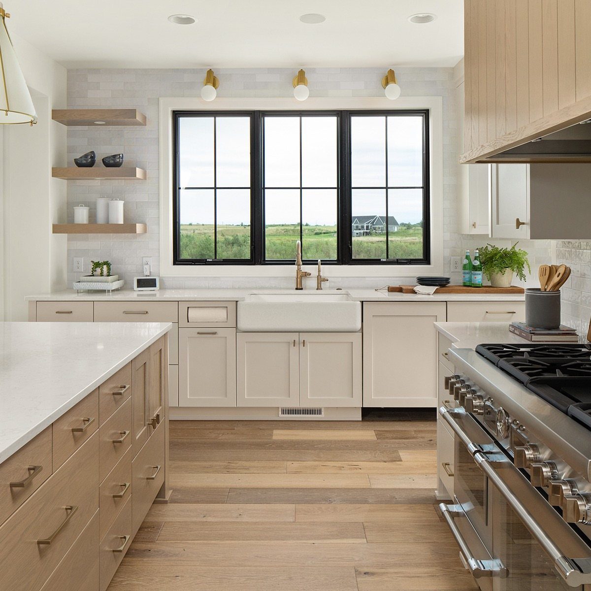 Black window frames in a bright kitchen with white cabinets and wooden floors