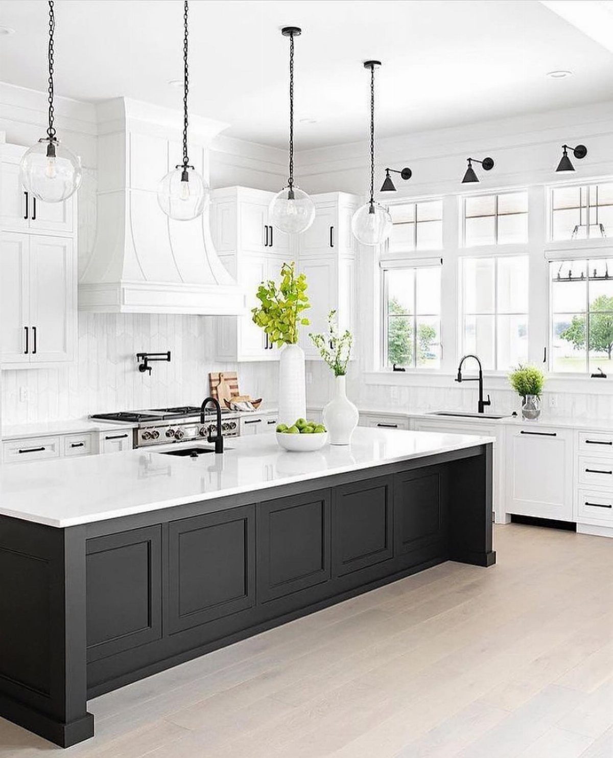 White kitchen cabinets with black hardware and a contrasting black center island.