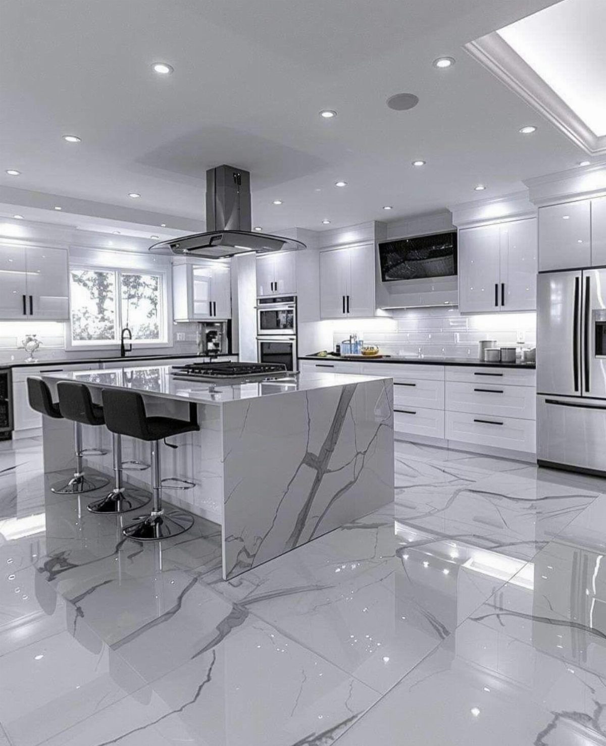 Modern white kitchen with marble island, black hardware, and polished marble flooring.