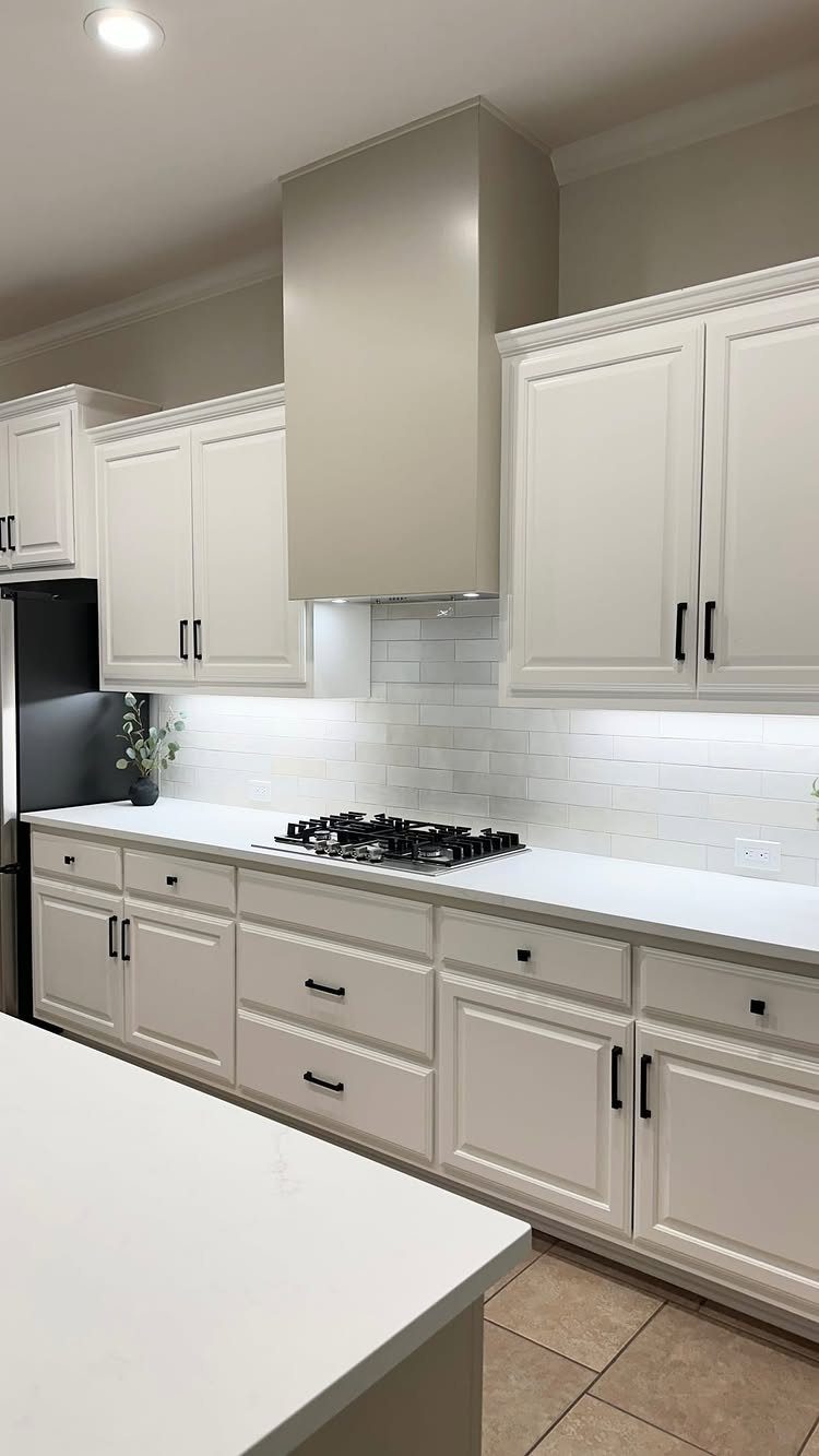 White shaker cabinets with matte black hardware and white quartz countertops in a kitchen.