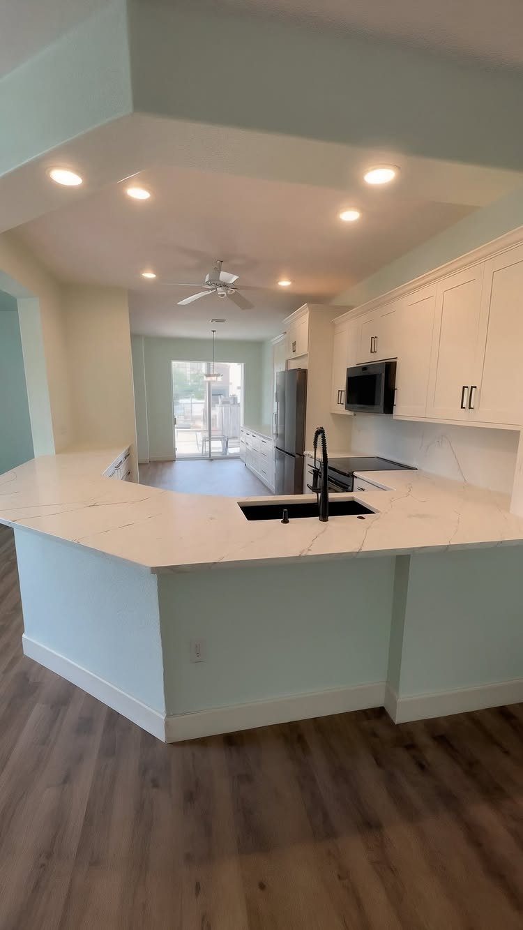 White marble-patterned quartz countertops in a kitchen with white cabinets and black hardware.