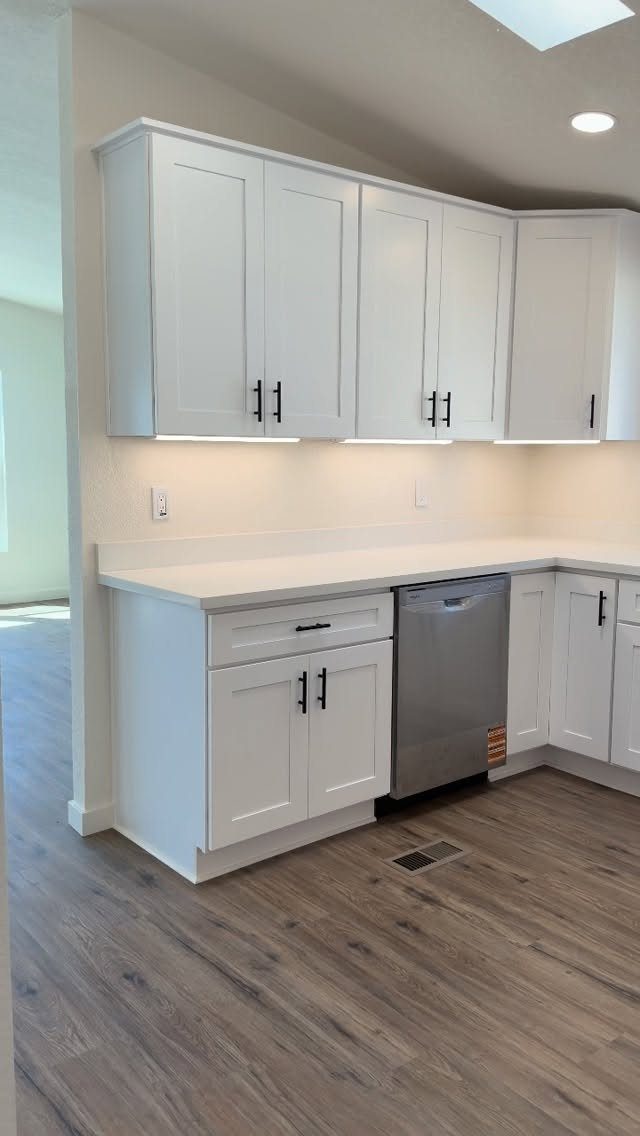 White shaker cabinets with black pulls and white countertops in a modern kitchen.