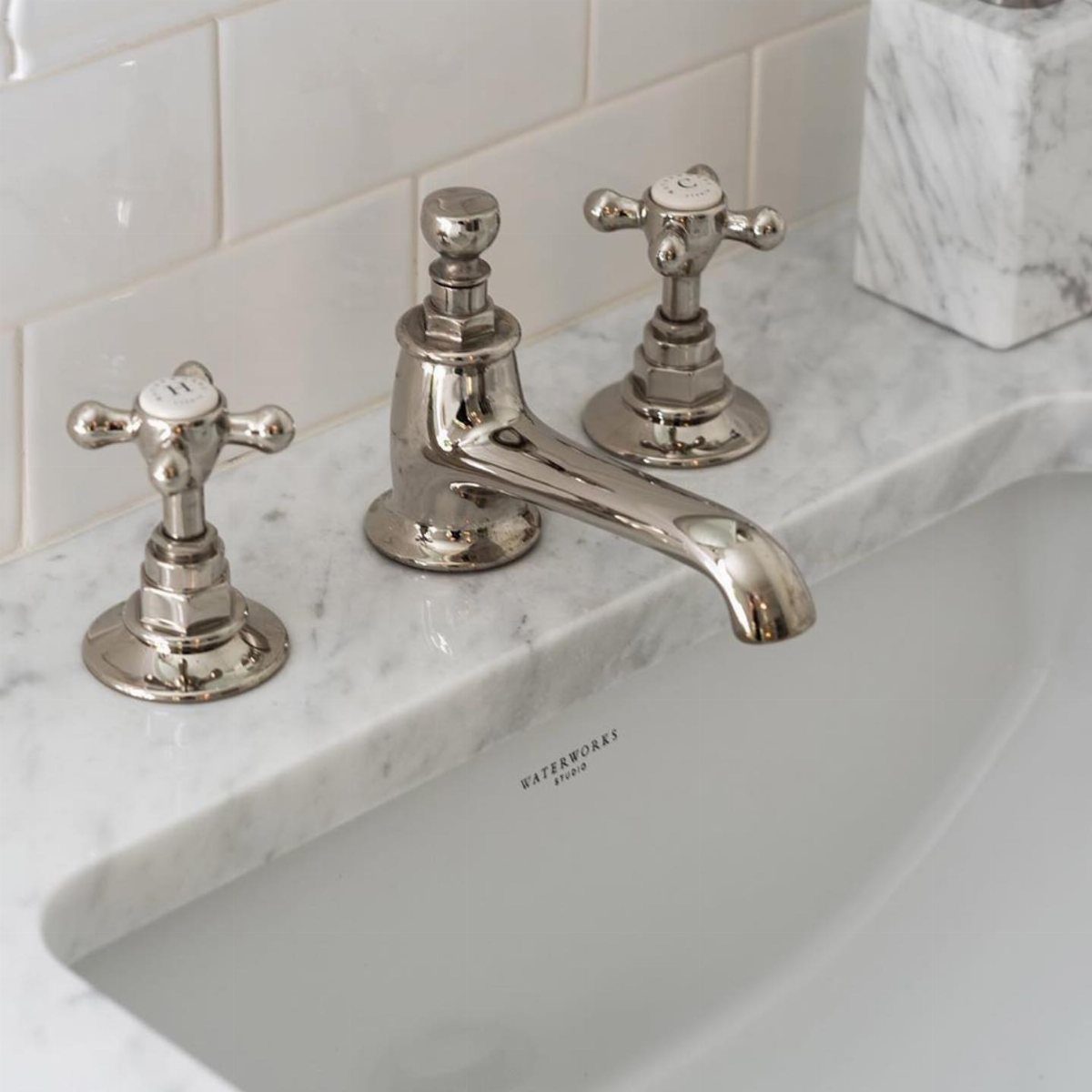 White subway tile backsplash behind a chrome faucet on a marble bathroom counter