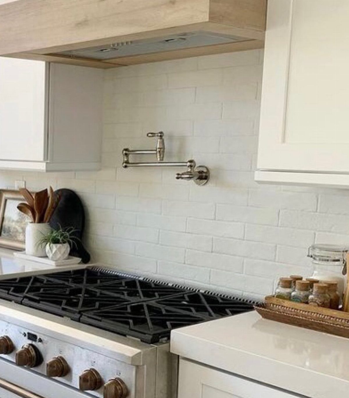 White subway tile backsplash in a kitchen with a silver pot filler faucet.
