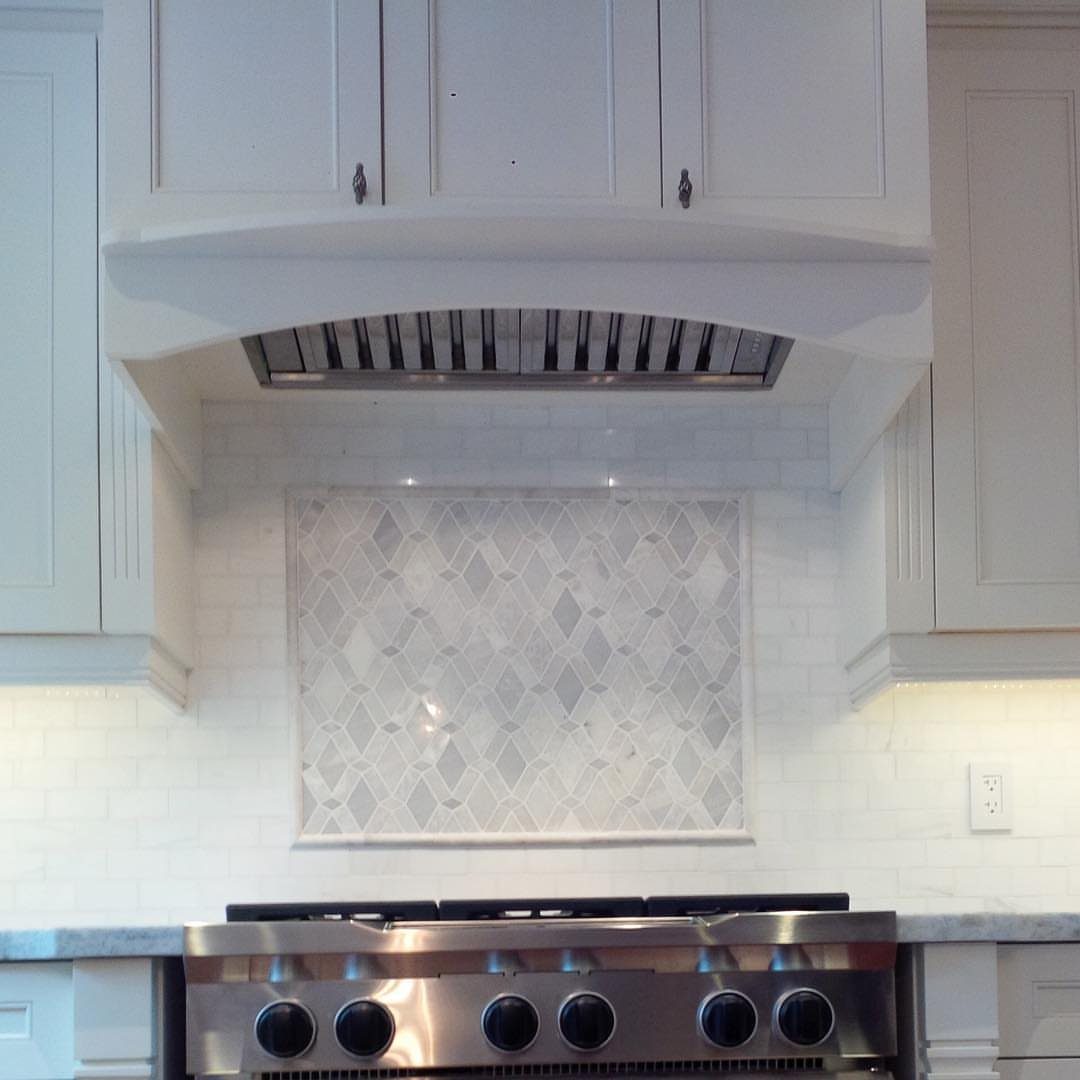 White subway tile backsplash with a decorative diamond pattern behind a gas stove.