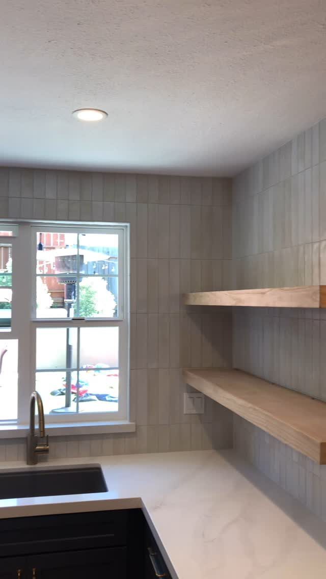 Vertical stacking white subway tile backsplash with floating wooden shelves and white countertop.