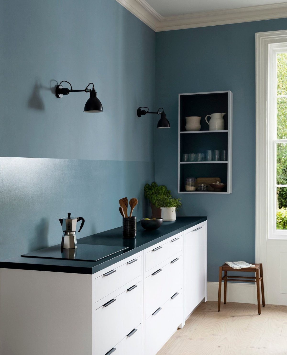 Muted blue kitchen walls with white lower cabinets and a black countertop