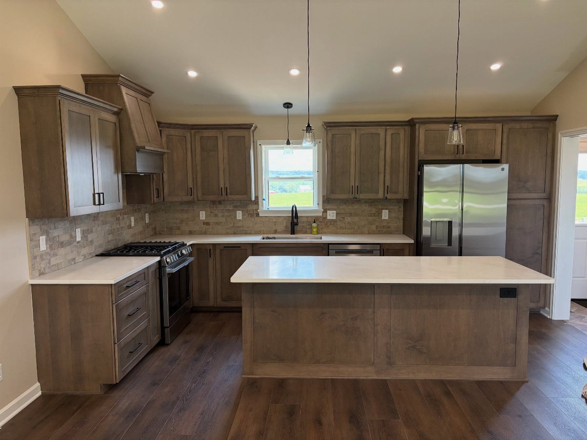Brown wood cabinets and dark wood floors in a modern kitchen with white countertops.