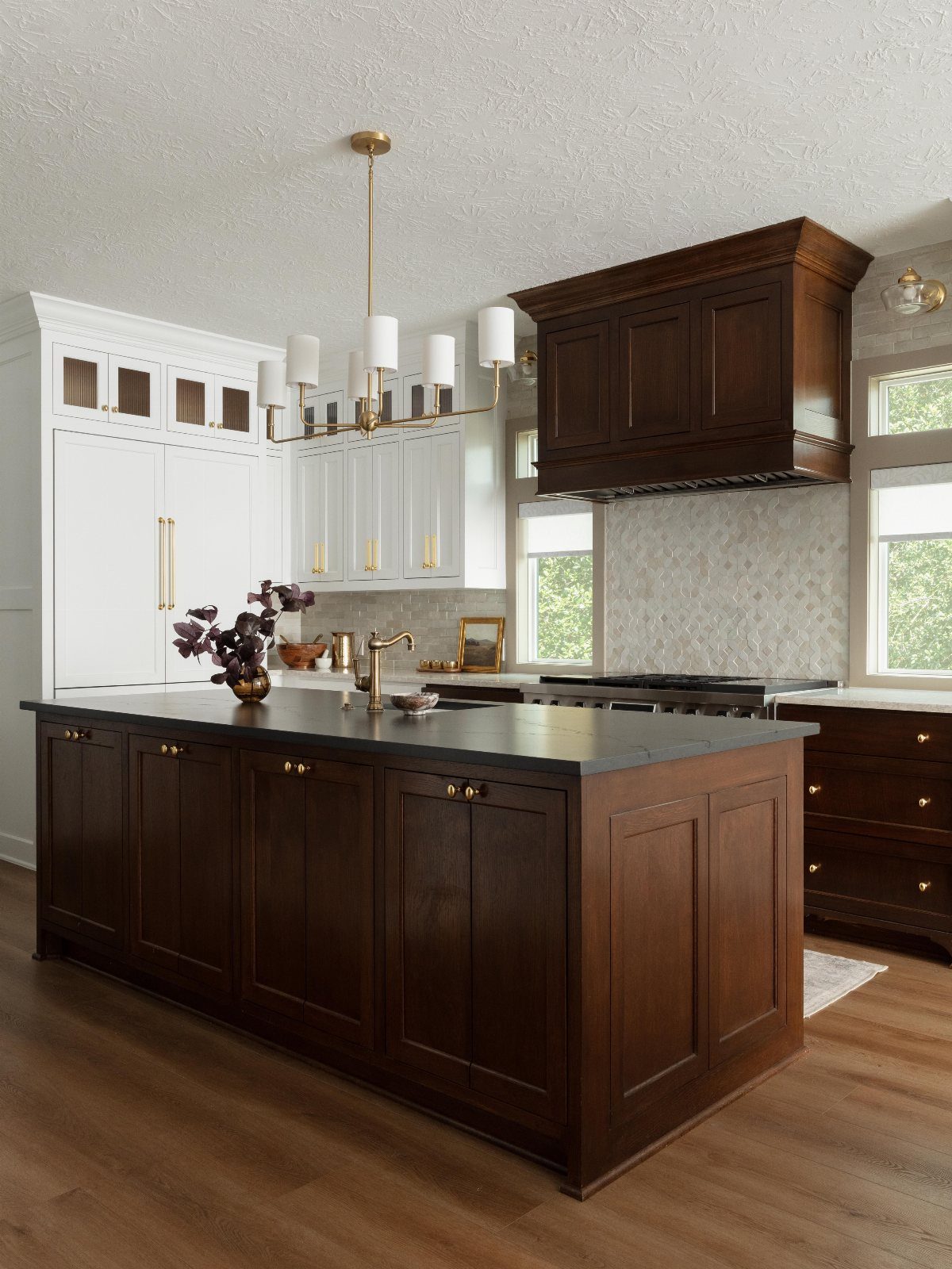 Dark wood kitchen island and cabinets paired with light brown wood flooring.