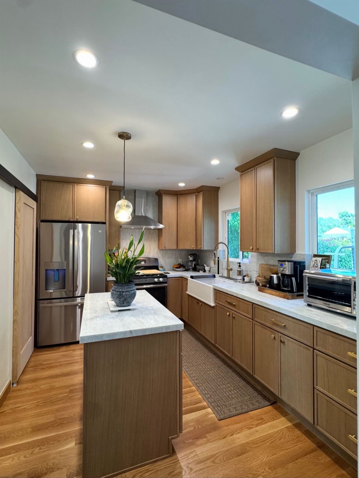 Light brown wood cabinets and matching wood floors in a bright modern kitchen